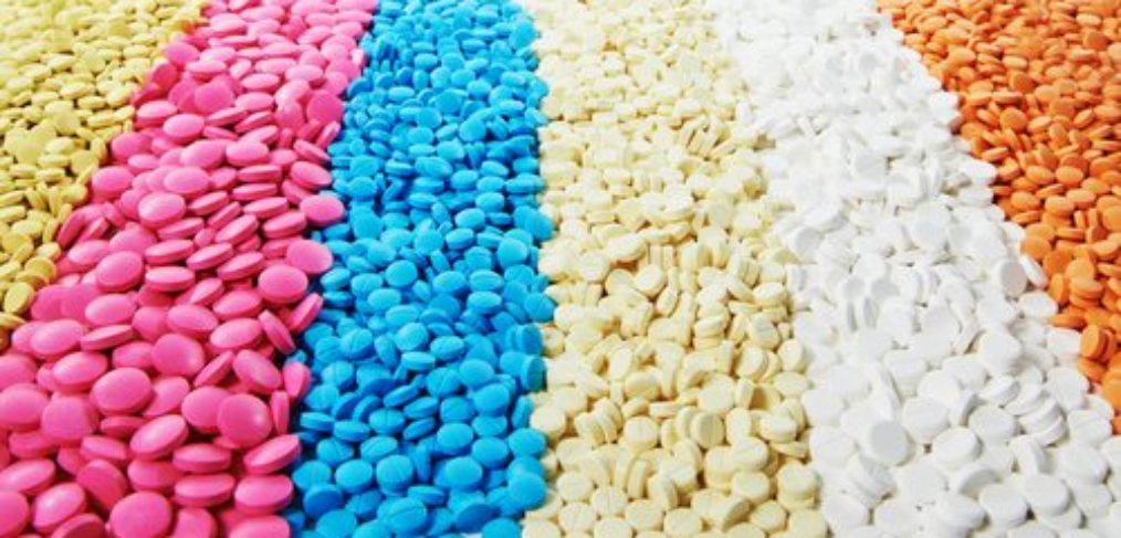 A pile of antibiotic pills in different colours.