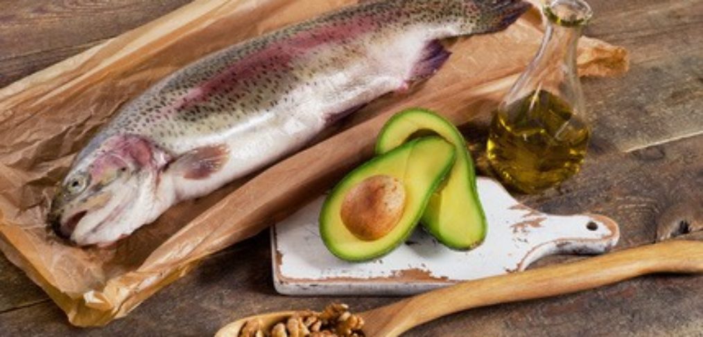 fish, avocado, walnuts laid out on a wooden board