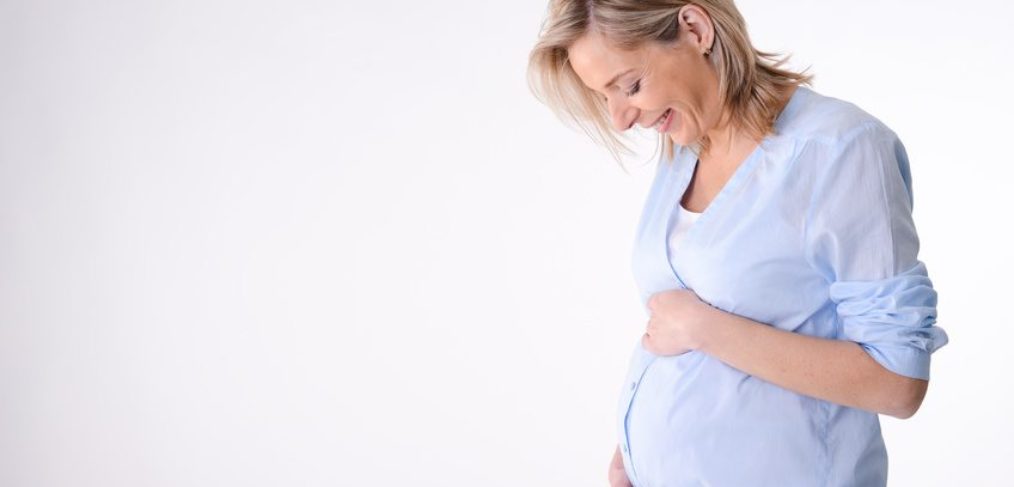Image of a happy pregnant woman wearing a blue shirt