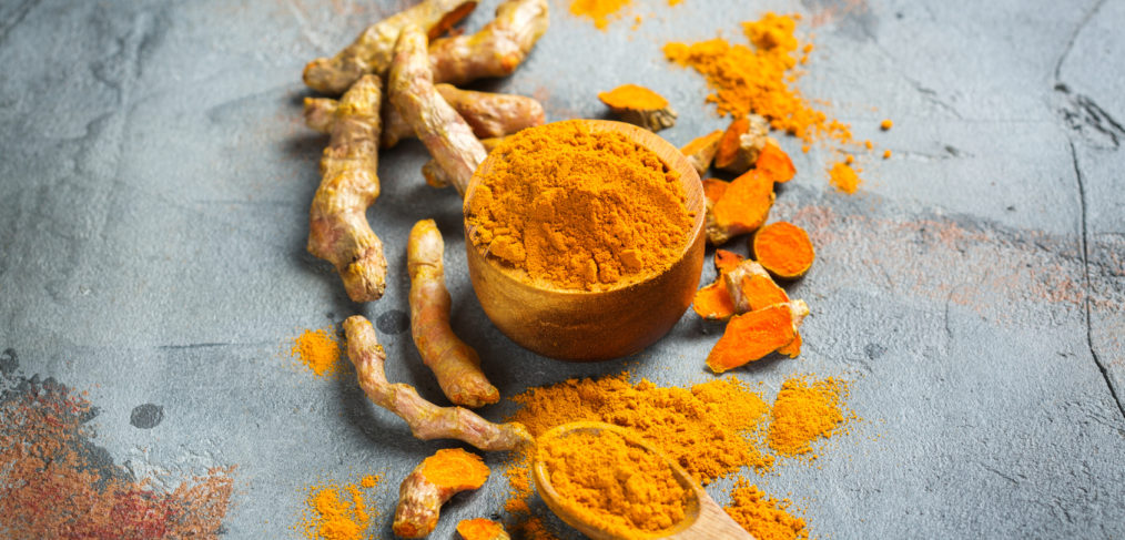 Raw organic orange turmeric root and powder, curcuma longa on a grunge cooking table.