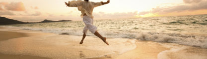 Woman embracing freedom, dancing along sandy beach with outstretched arms and waves at her feet