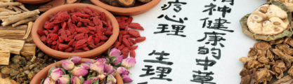 Chinese herbs used in alternative herbal medicine with calligraphy script on rice paper. Translation reads as traditional ancient chinese medicine to heal mind, body and spirit.
