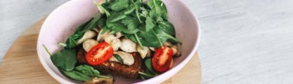 A picture of some tomatoes, spinach and bread in a pink bowl.