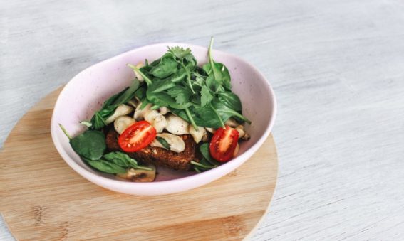 A picture of some tomatoes, spinach and bread in a pink bowl.