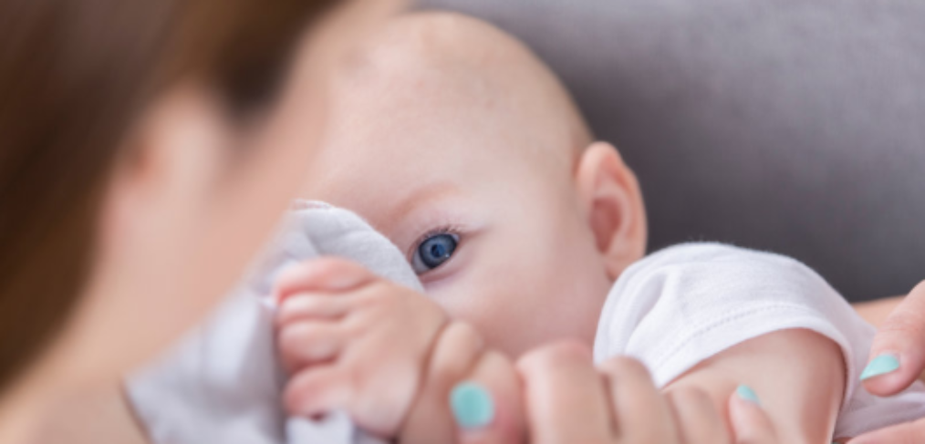 A lady with blue nail polish breastfeeding a baby