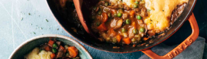 Shepherds pie consisting of mashed potato and a mixture of vegetables in a gravy underneath served in a casserole dish