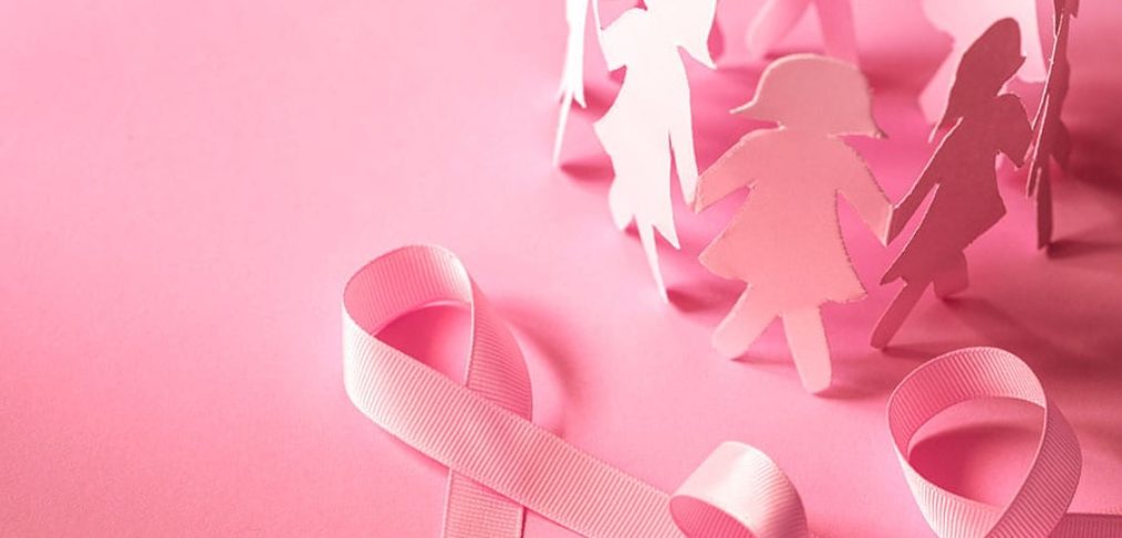 Pink cut outs of women in paper with a pink ribbon on a pink background